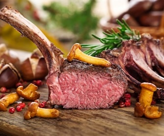 Auf einem Holzbrett liegt ein Stück Fleisch. Es ist aufgeschnitten und das rosa Fleisch ist zu sehen.